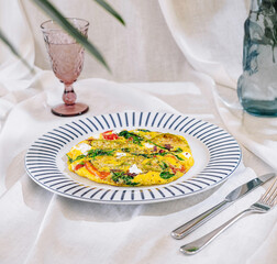 Delicious omelette with vegetables served on white tablecloth for brunch