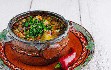 Delicious soup with vegetables and herbs served in rustic bowl