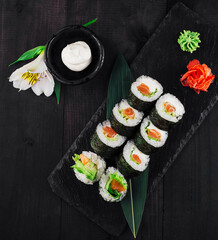 Fresh sushi rolls with salmon and avocado on black stone serving plate