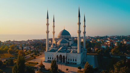 Fototapeta premium Stunning aerial view of a grand mosque with tall minarets against a clear sky, showcasing beautiful architecture and serene landscape.