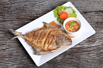 Deep Fried Pomfret with Fish Sauce isolated shot from above on a rustic texture 