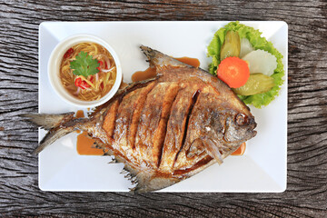 Deep Fried Pomfret with Fish Sauce isolated shot from above on a rustic texture 