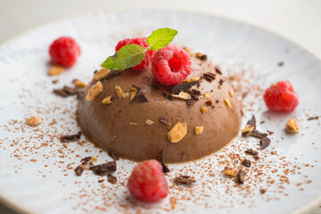 Dark chocolate flan with almonds. Decorated with cocoa powder and raspberries.