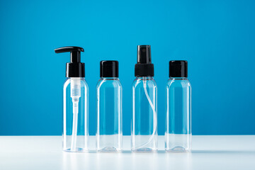 Clear plastic bottles with black caps arranged on a white surface against a bright blue background