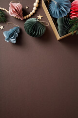 Pastel paper Christmas decorations and ornaments on a dark brown background. Flat lay, top view, vertical. © photoguns