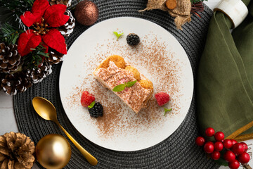 Italian tiramisu with red berry cream. Top view table with Christmas decorations.