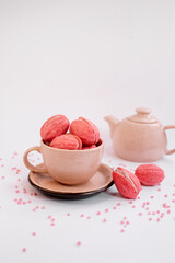 Pink walnut-shaped cookies (oreshki) in a beige cup near the tea-pot