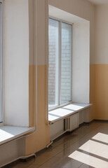 A window with a white frame and a white sill sits in a room with a yellow wall