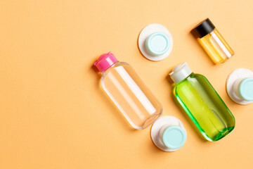 Group of small bottles for travelling on colored background. Copy space for your ideas. Flat lay composition of cosmetic products. Top view of cream containers with cotton pads