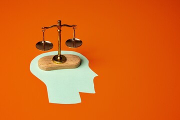 Balance scale placed on top of a green paper cutout shaped like a human head. Weighing options,...