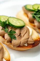 Savory canapes topped with creamy spread and cucumber slices served on toasted bread at a casual gathering
