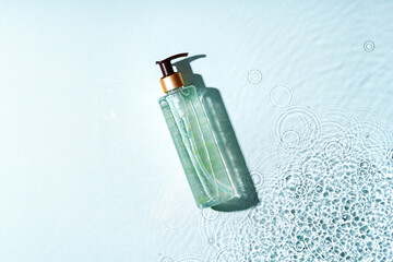 Clear bottle of gel product resting on a light blue surface with water droplets