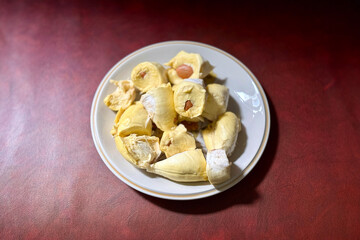 Plate of Fresh Durian Pieces on a Red Surface - Tropical Fruit Ready to Eat