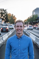 Obraz premium Smiling man in blue shirt standing on traffic-lined city street