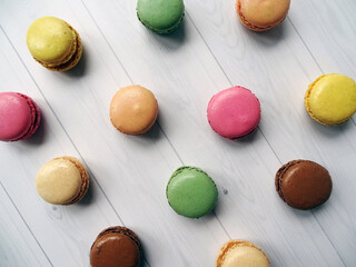 Widok z góry na kolorowe makaroniki ułożone w regularny wzór na białym drewnianym tle © KJP Photography