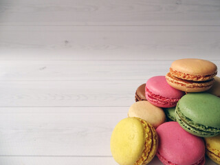 Kolorowe francuskie makaroniki na białym drewnianym tle z dużym miejscem na tekst