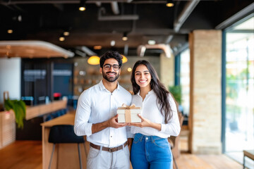 Fototapeta premium young indian couple holding gift box at office