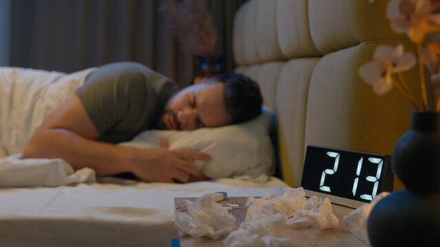 Sick man lying on bed illness runny nose woman holding glass water care couple family drink refreshing virus unhealthy wife husband boyfriend girlfriend sneeze suffering help support bedroom flu love