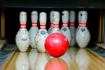 A bowling ball is in the middle of a row of bowling pins. The bowling ball is positioned in the middle of the row of pins, with the pins on either side of it