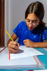 Young Girl Focused on Homework, Writing in Notebook at Study Desk
