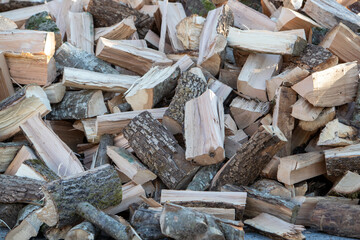 Tas de morceaux de bois pour le chauffage poser en extérieur, attendant d'être rangé dans un abri. Bois coupé pour le chauffage des maisons, prêt à être stocker pour sécher.