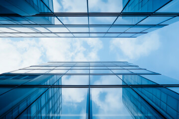 Obraz premium The sky is blue and the clouds are white. The buildings are tall and have many windows. The glass windows reflect the sky and clouds, creating a sense of depth and height