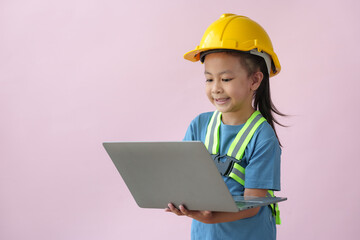 Young Asian girls' future dream careers as engineers and architects, wearing yellow helmets and fluorescent harnesses for work, stand holding notebook computers, smiling happily.