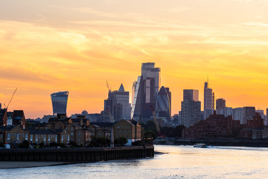 A stunning city skyline at sunset showcasing iconic skyscrapers by the river, highlighting the dynamic cityscape and beautiful contrast of nature and architecture in London