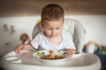 A toddler enjoying a meal while sitting in a high chair in a cozy home setting during afternoon