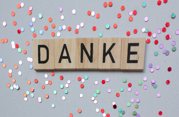 Thank you card with german language DANKE on wooden block on background with shiny glitters, panorama