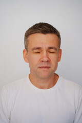 Portrait of a middle-aged man with closed eyes in a white t-shirt on a white background. photo posing. men's physical and mental health. photo for documents