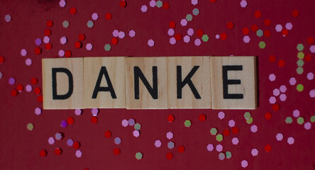 Thank you card with german language DANKE on wooden block on background with shiny glitters, panorama