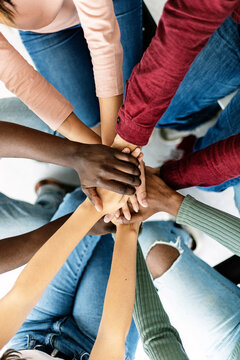 Vertical shot of young group of diverse people stacking hands together showing unity and cooperation. Teamwork concept