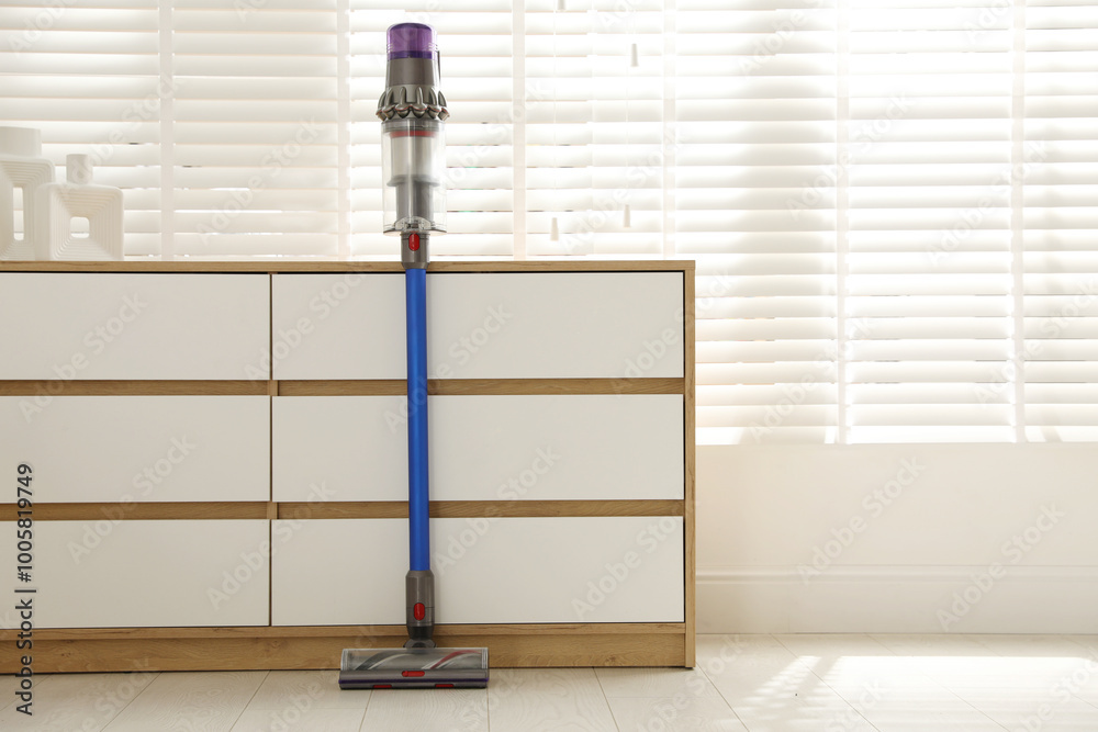 Poster One cordless vacuum cleaner leaning on chest of drawers indoors