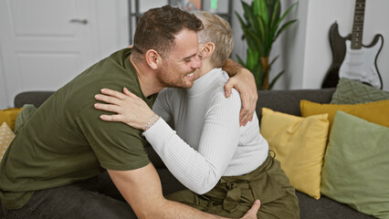 Fototapeta premium A smiling man hugs a woman affectionately in a cozy home interior with decorative pillows and a guitar.