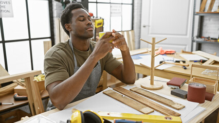 A young african american man enjoys a coffee break in an indoor carpentry workshop setting.