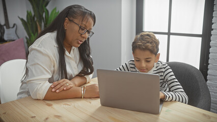 A mother and son engaging with technology in the living room, depicting family, togetherness, and home education.