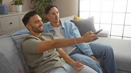 Obraz premium Men relaxing at home, watching tv in a cozy living room, conveying a sense of love and togetherness.