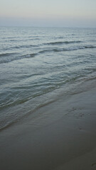 Serene seaside promenade with gentle waves and sandy shore at twilight.