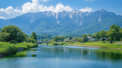 Fototapeta premium The fresh green landscapes of Kamikachi, with the tranquil Azusa River and the towering peaks of the Hotaka Mountains creating a serene and picturesque scene.