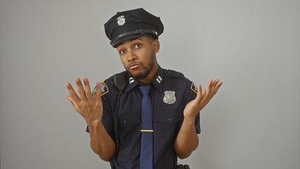 Confused african american male police officer shrugging in uniform against a white backdrop.