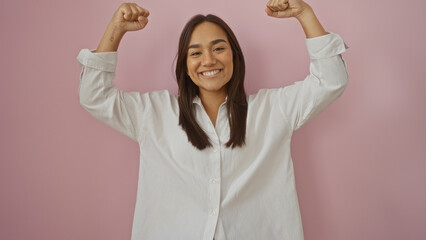 Beautiful young hispanic woman in white shirt over isolated pink background making a strong gesture...