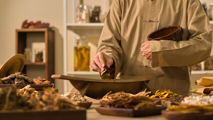 Image template with a classic medicine room backdrop showcasing a doctor uses a traditional wooden mill to gently ground herbal leaves while surrounded by dried herbs used in traditional medicine.
