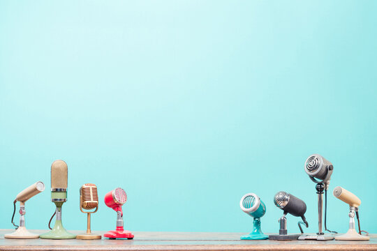 Retro microphones for press conference or interview on table front mint blue background. Vintage old style filtered photo