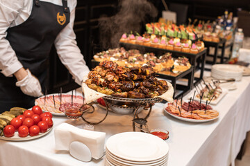 Table with food. Banquet hall. The waiter sets the table.