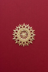 Snowflakes are made of straw on a red background. Christmas decor. Straw star. Top view. Straw weaving. Lutsk, Ukraine