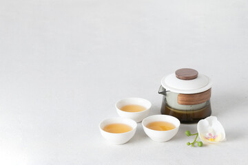 Contemporary tea ceremony concept with crystal teapot and white bowls on the white background, copy space