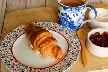 croissant and cup of coffee with jam and cream cheese 