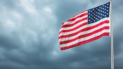 Obraz premium An American flag waves against a backdrop of dark, cloudy skies, symbolizing patriotism and resilience.