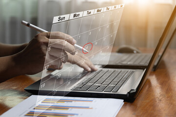 Businessman points pen at virtual table Appointment schedule On the calendar to make a meeting, project management concept Analysts work with computers in management systems to make reports.